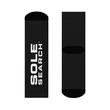 A pair of black crew socks shown flat against a white background, with one sock displaying the white vertical text 'SOLE SEARCH' and the other showing the ribbed arch support band.